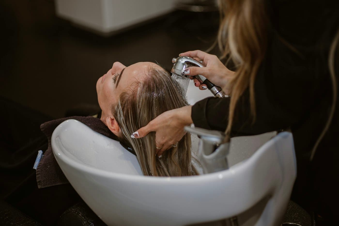 A stylist washing a client’s hair in a salon