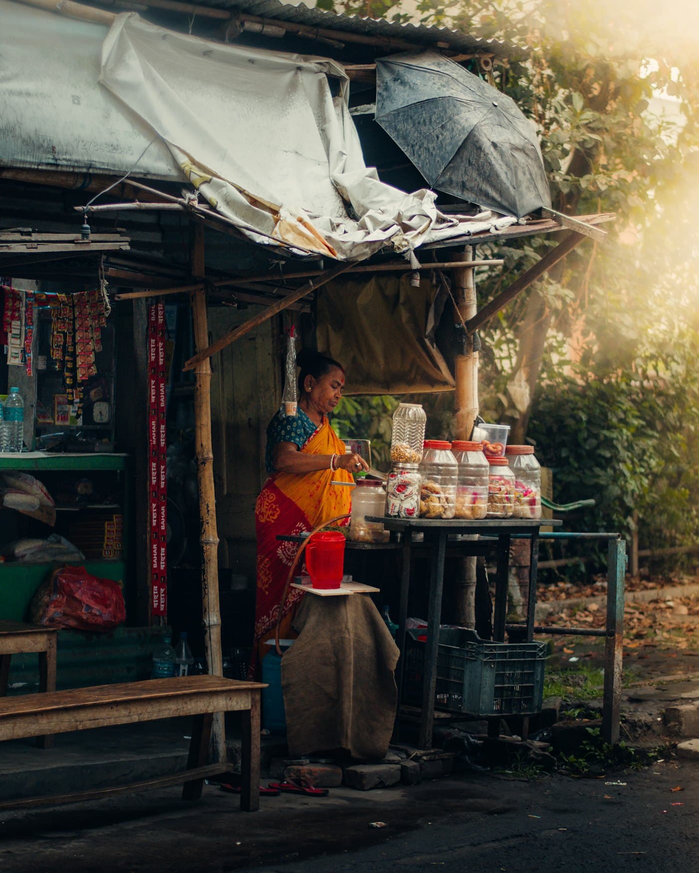 A woman running a small snack stall stocked with jars and packets